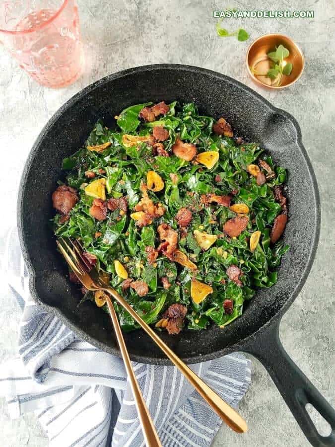 Brazilian garlicky collard greens with bacon in a skillet with garnish on the side (couve a mineira com bacom)