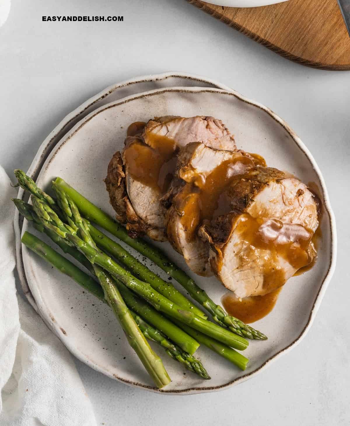 close up of the roasted sliced meat with sauce and asparagus in a plate. 