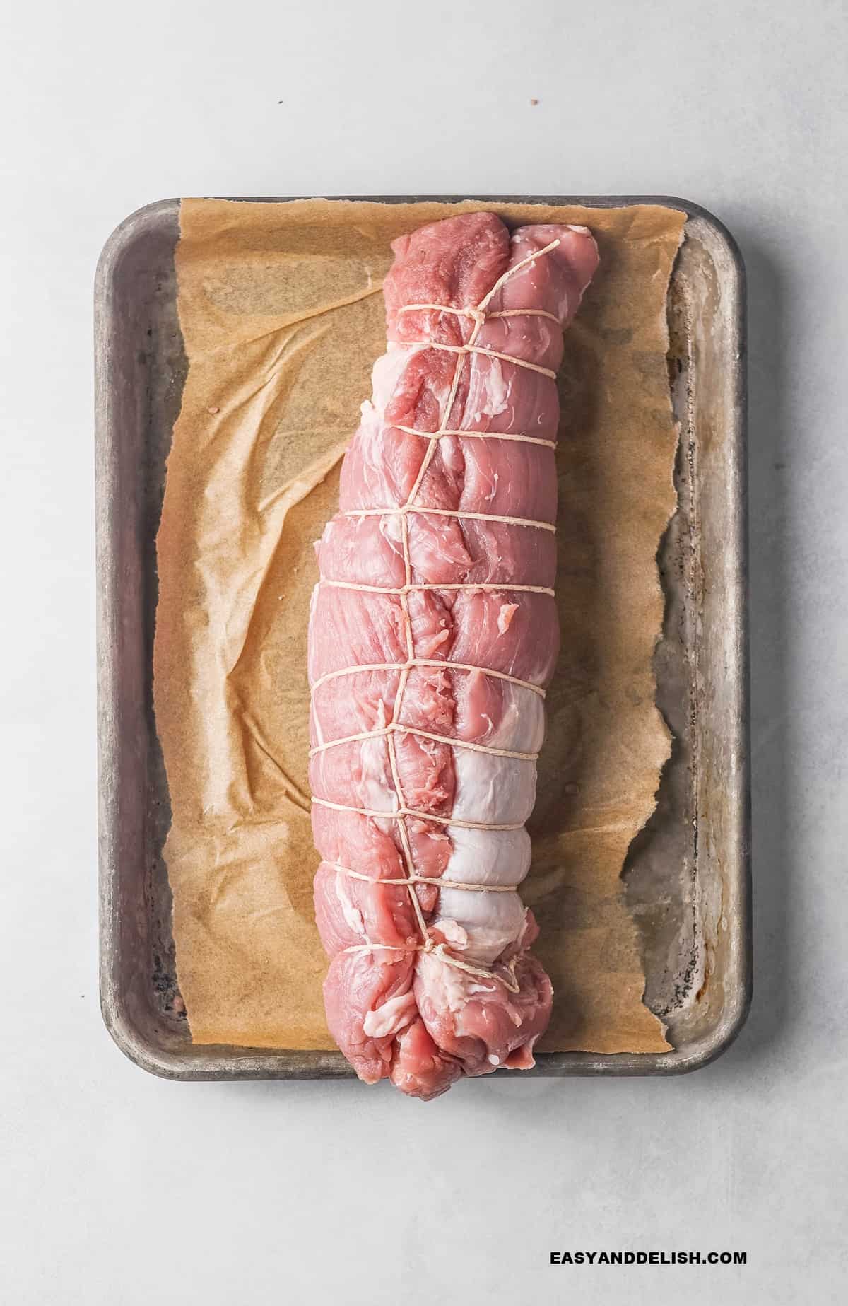 loins tied with a twine in a baking sheet.