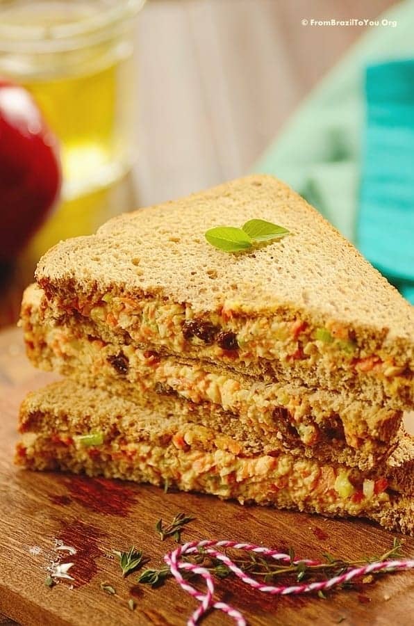 A pile of halved chicken salad sandwich ona  cutting board.