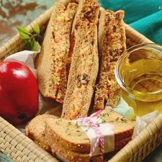 sliced chicken salad sandwiches with a red apple in a basket.