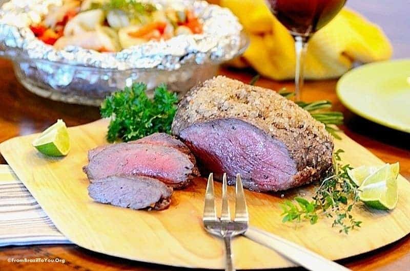 oven baked rump cap in a cutting baord served with vegetables and wine