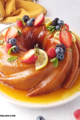 close up of whole easy sourdough bread pudding with caramel sauce and berries on top.