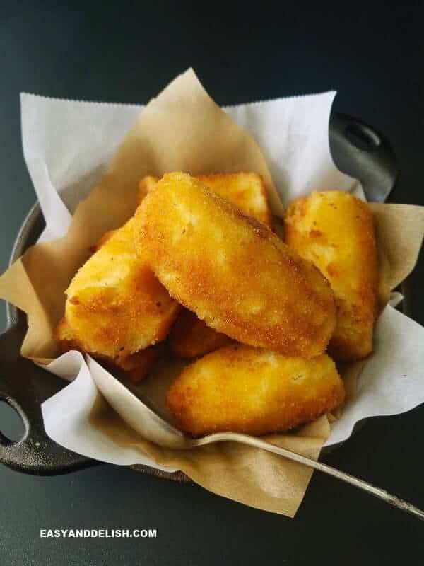A small iron skillet filled with a stack of golden-brown deep fried bananas