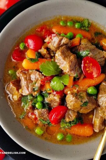 A bowl of Brazilian beef stew or picadinho with red tomatoes, green peas and cilantro, and orange carrots