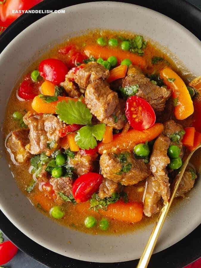 a bowl of picadinho de carne with a spoon on the side 