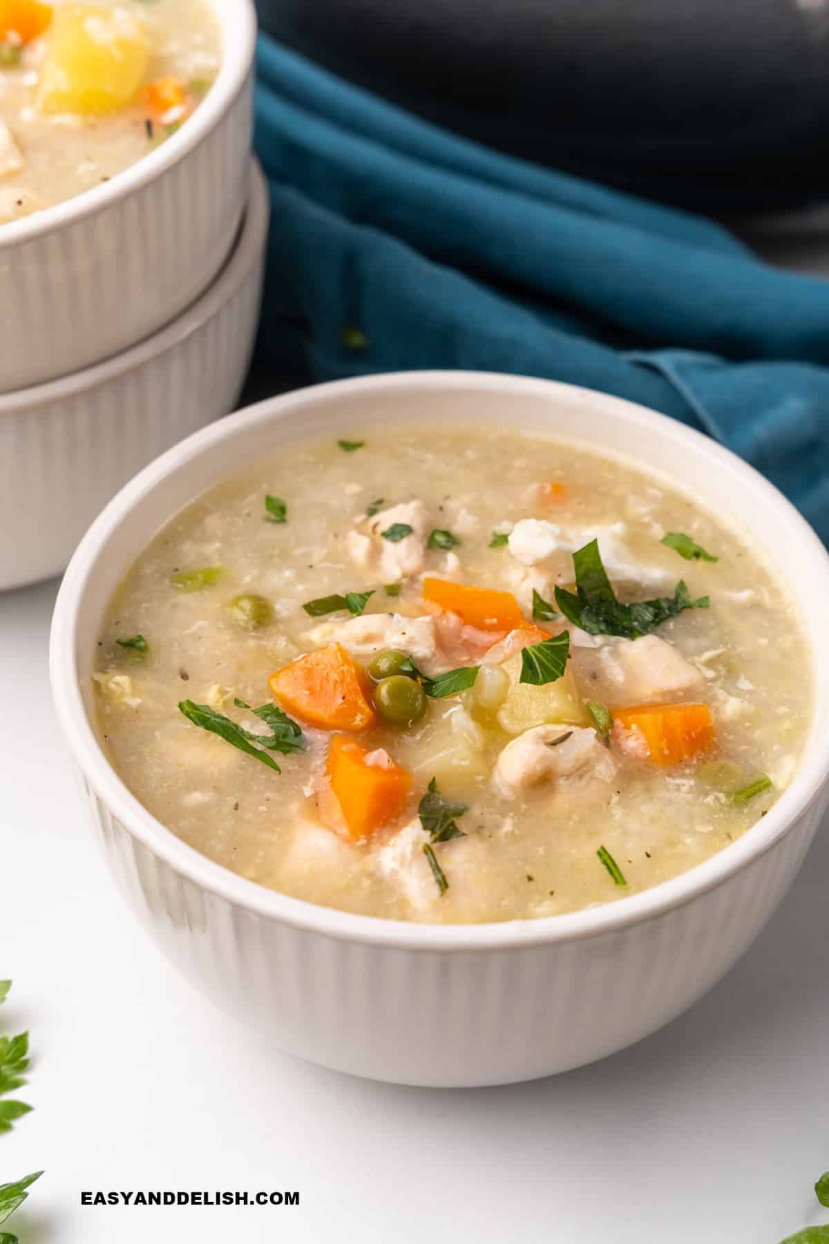 a bowl of chicken soup on a table with a napkin on the side.