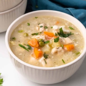 a bowl of chicken soup on a table with a napkin on the side.