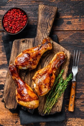 grilled chicken drumsticks over a cutting board with herbs