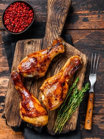 grilled chicken drumsticks over a cutting board with herbs