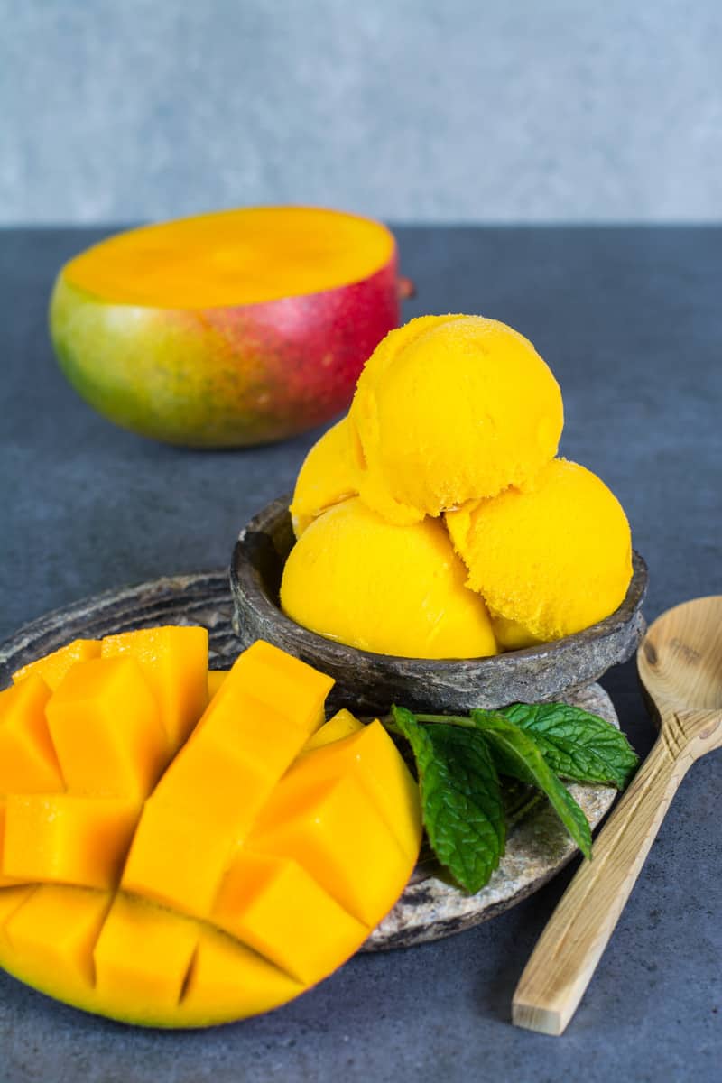 A bowl of ice cream and mango on the side