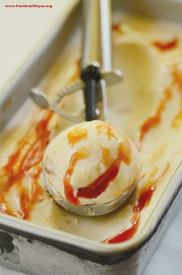 Tray and scoop of sorvete nata goiaba or guava cream ice cream, with red guava sauce swirls