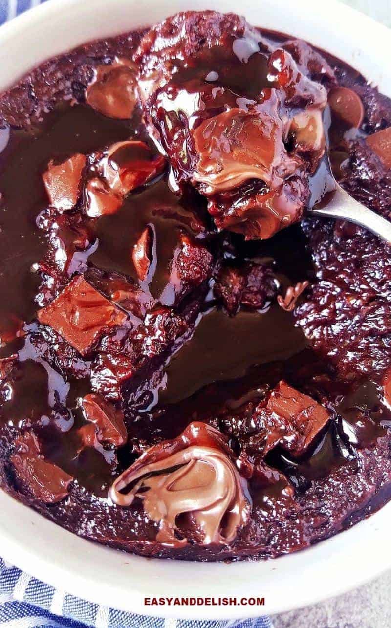 close up of chocolate mug cake with chocolate sauce being spooned