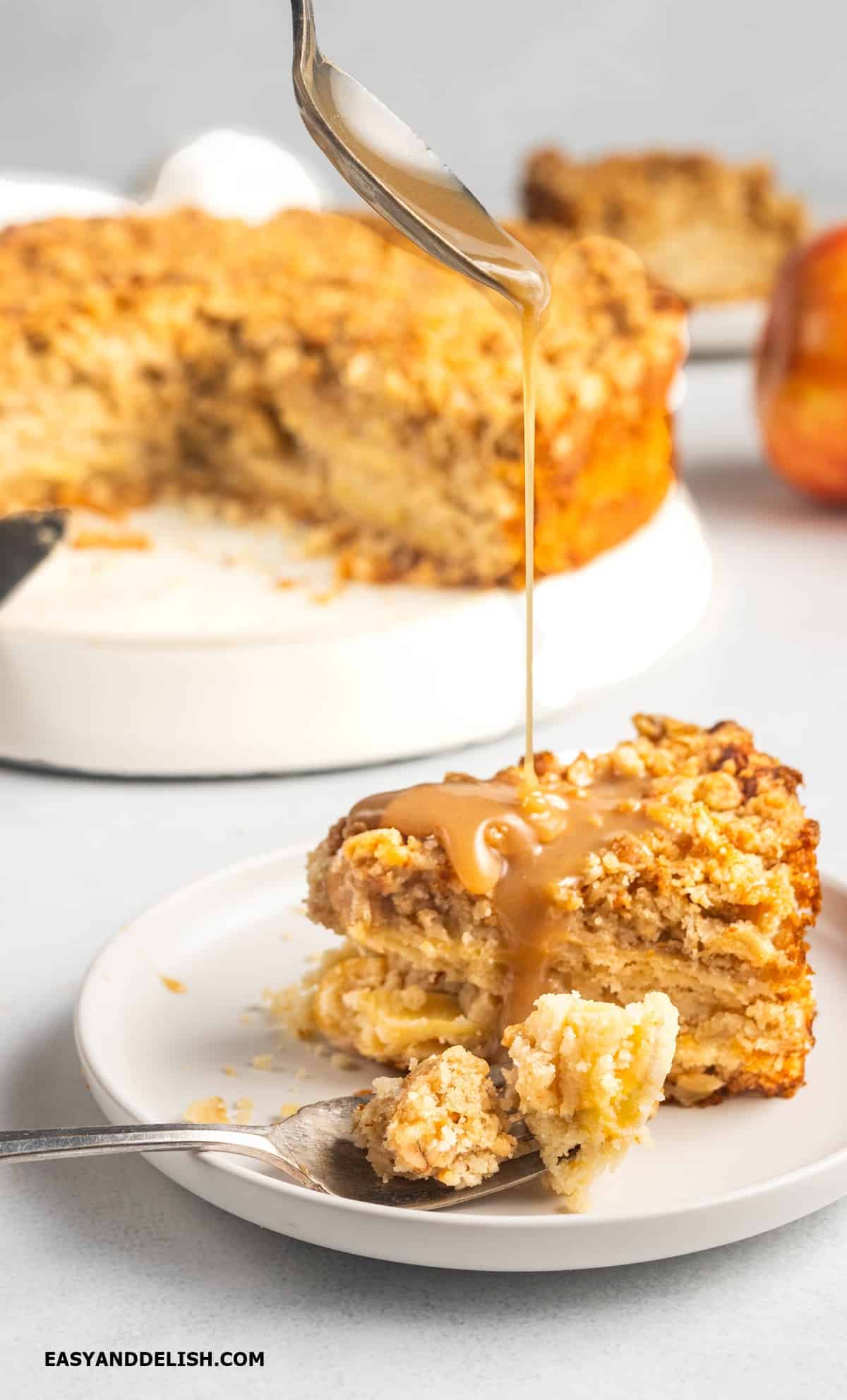 sppon of caramel drizzled over a slice of apple streusel cake. 