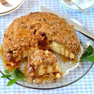 A plate of sliced apple streusel cake on a table with a blue gingham table cloth