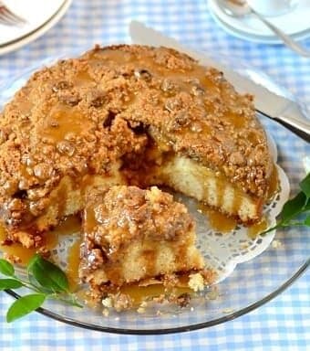 A plate of sliced apple streusel cake on a table with a blue gingham table cloth