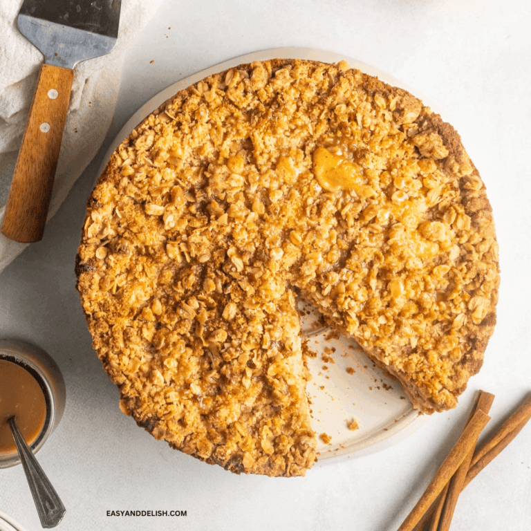 caramel apple cake with streusel topping partially sliced in a plate.