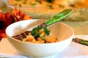 Bowl of baked rice casserole or arroz de forno cremoso with a green handle spoon