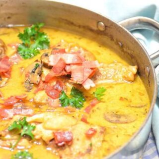 A skillet full of beer braised chicken with sauce