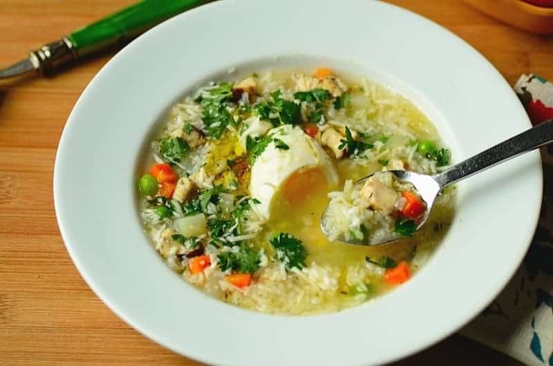 canja de galinha chicken soup in a white bowl, garnished with herbs