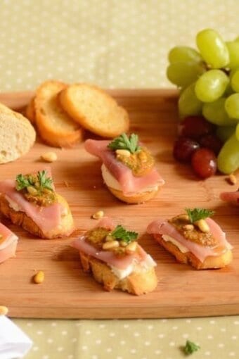 crostini with cheese on a serving board with green grapes
