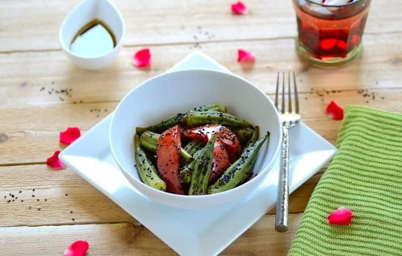 A bowl of okra salad with garnishes on the side