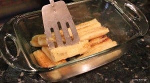 Fried bananas being arranged in a glass pan A baking dish with cooked bananas