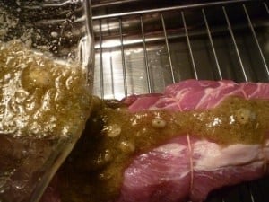 pouring and spreading garlic mixture over pork loin