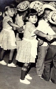 A vintage photo of a group of children dancing and posing for the camera