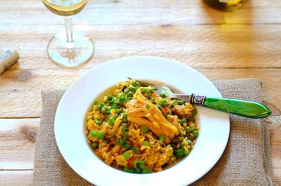 galinhadamade of saffron rice with chicken and vegetables, in a white bowl with a green handled fork