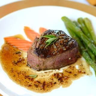 A plate of filet mignon with carrots and asparagus
