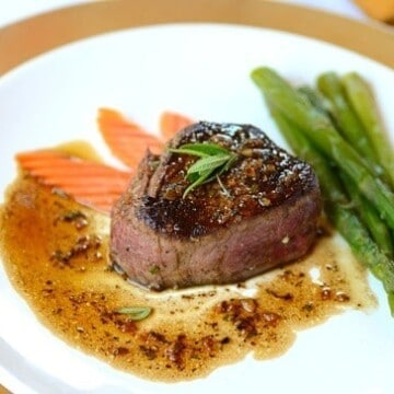 A plate of filet mignon with carrots and asparagus