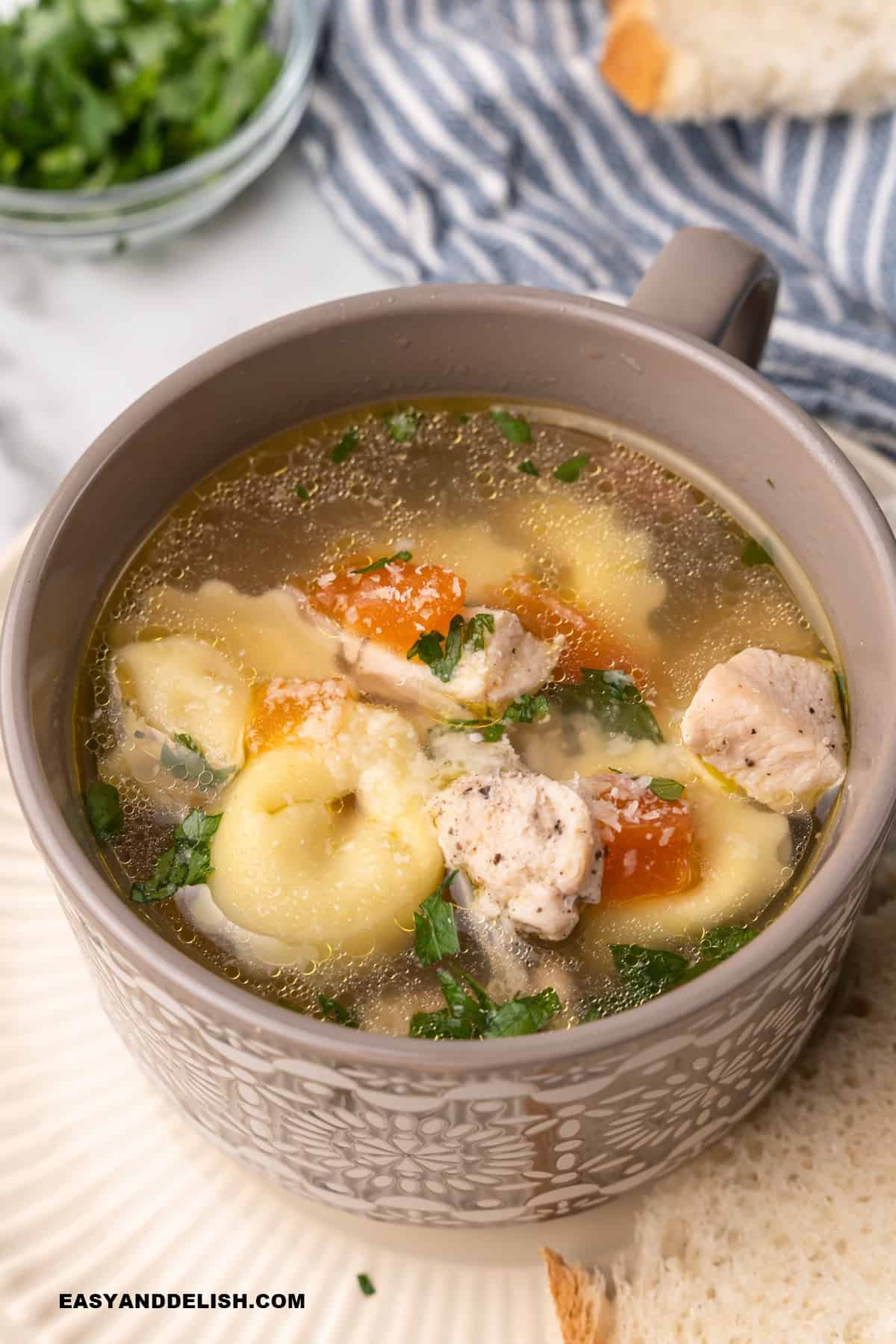 a bowl of chicken tortellini soup with a napkin on the side