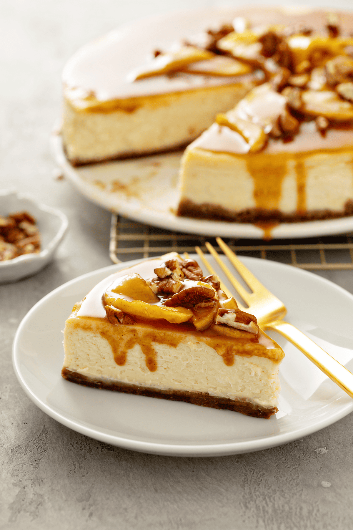 a slice of low-carb cheesecake in a plate topped with a caramel apple topping.