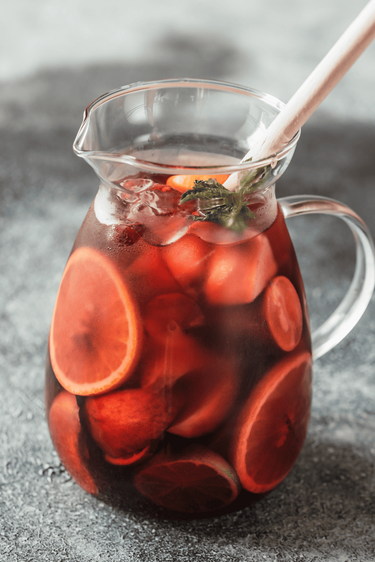 a pitcher with juices, spirit, and fruit garnishes
