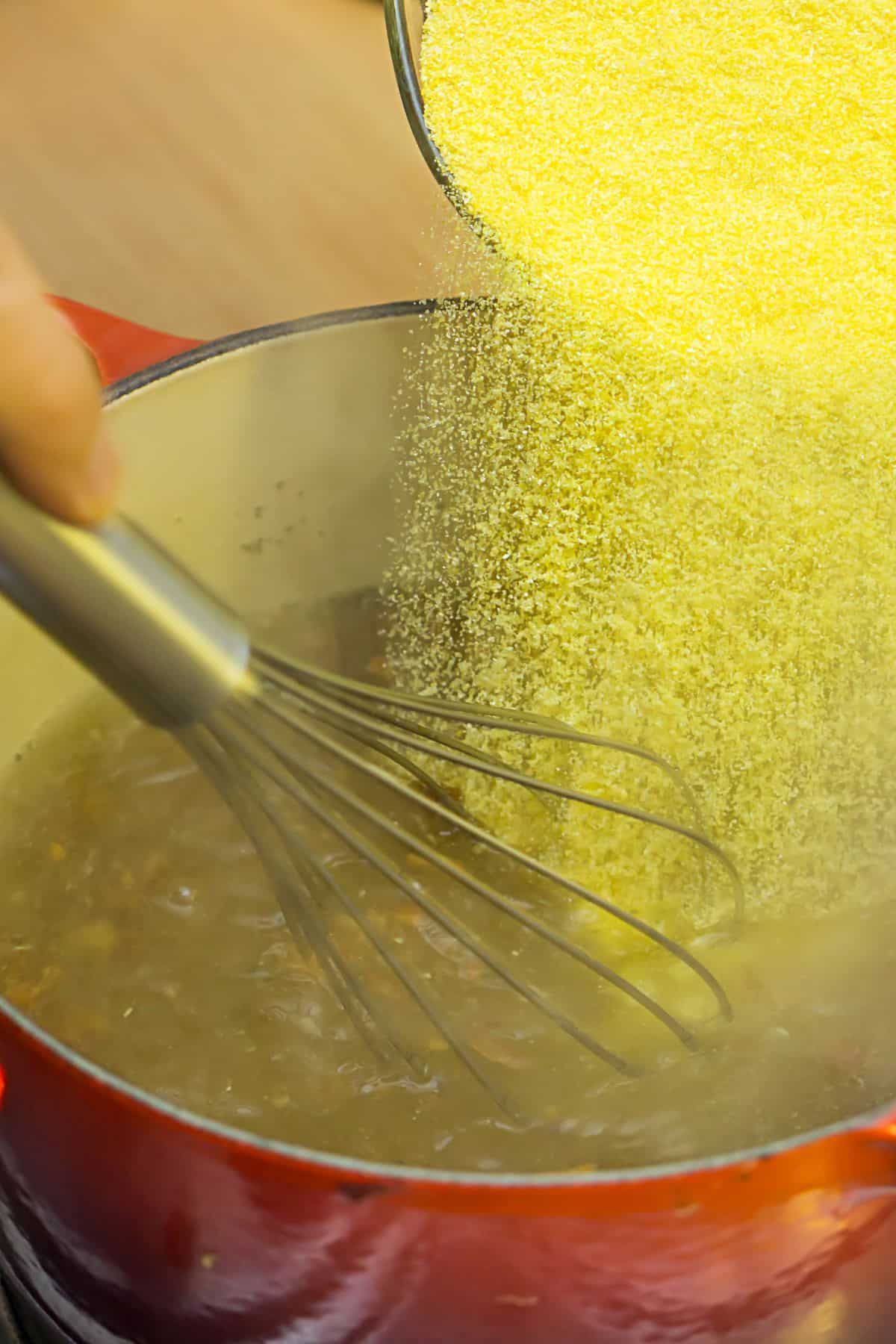Cornmeal added to a pan of boiling water. 
