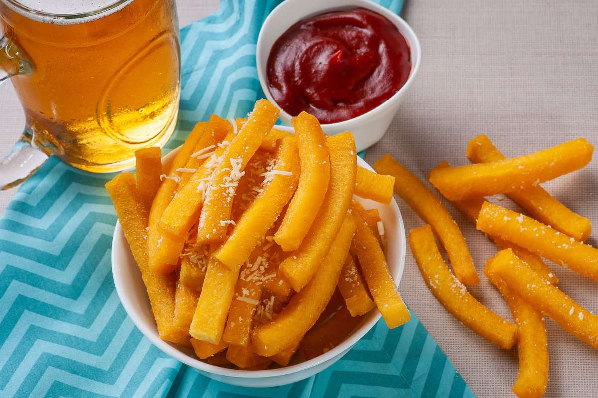 Gluten-free corn sticks with ketchup on a side bowl and a glass of beer. 