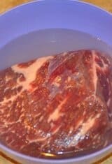 desalting meat covered with water in a purple bowl