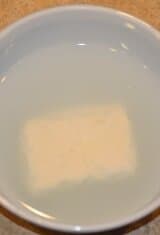 desalting halloumi cheese covered with water in a bowl