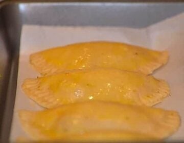 filled and sealed empanada disc with the edges crimpled and brushed with egg yolk