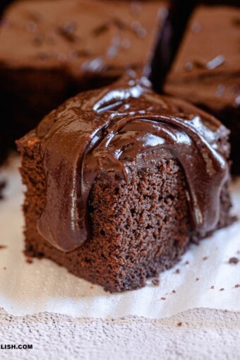 close up of a slice of dairy-free chocolate cake over a parchment paper