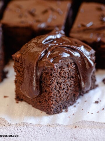 close up of a slice of dairy-free chocolate cake over a parchment paper