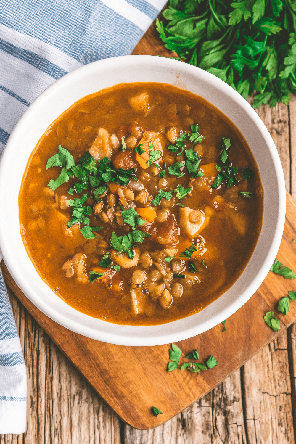 a bowl of warm food on a table with fresh herbs on the side. 