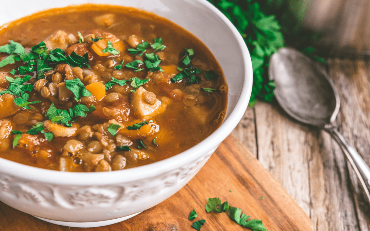 a bowl of beef lentil soup on a table.