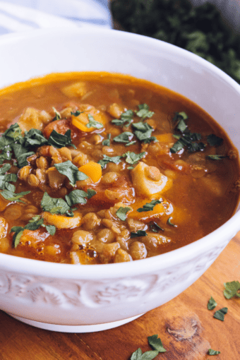 A bowl of our lentil soup recipe with beef and vegetables served on a table.