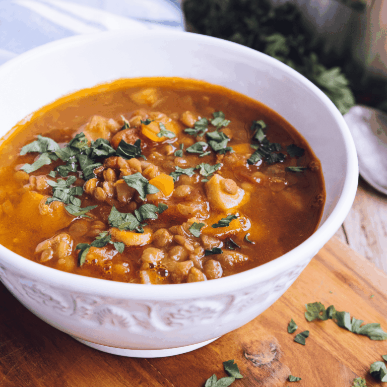 A bowl of our lentil soup recipe with beef and vegetables served on a table.