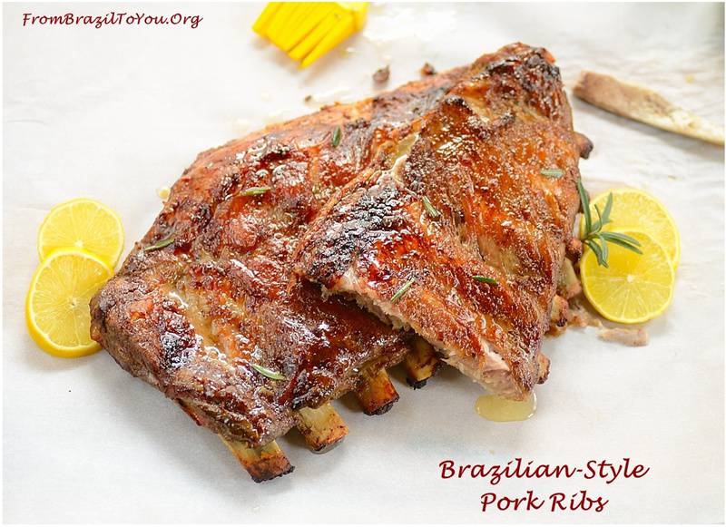 A rack of grilled Brazilian Style Pork ribs with wedges of lemon