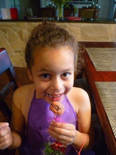 A little girl sitting at a table eating food 