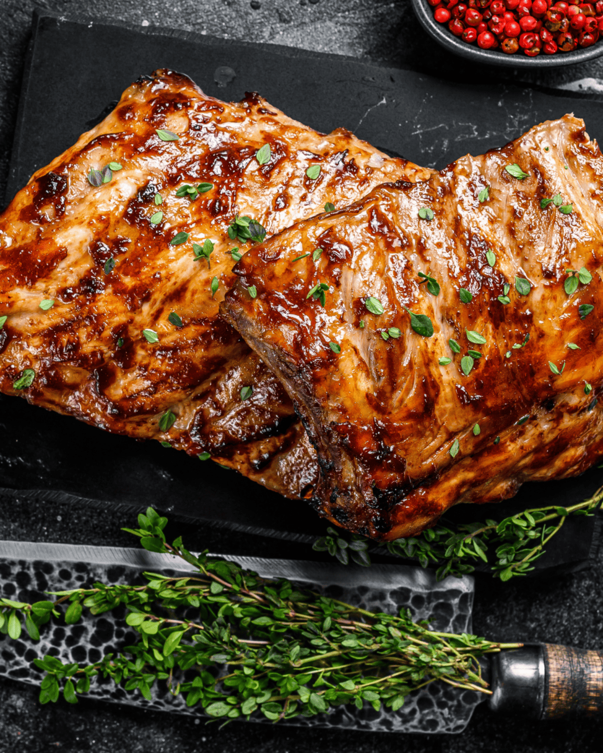 halved rack of baked pork ribs that were later grilled on the griddle and served with fresh herbs.