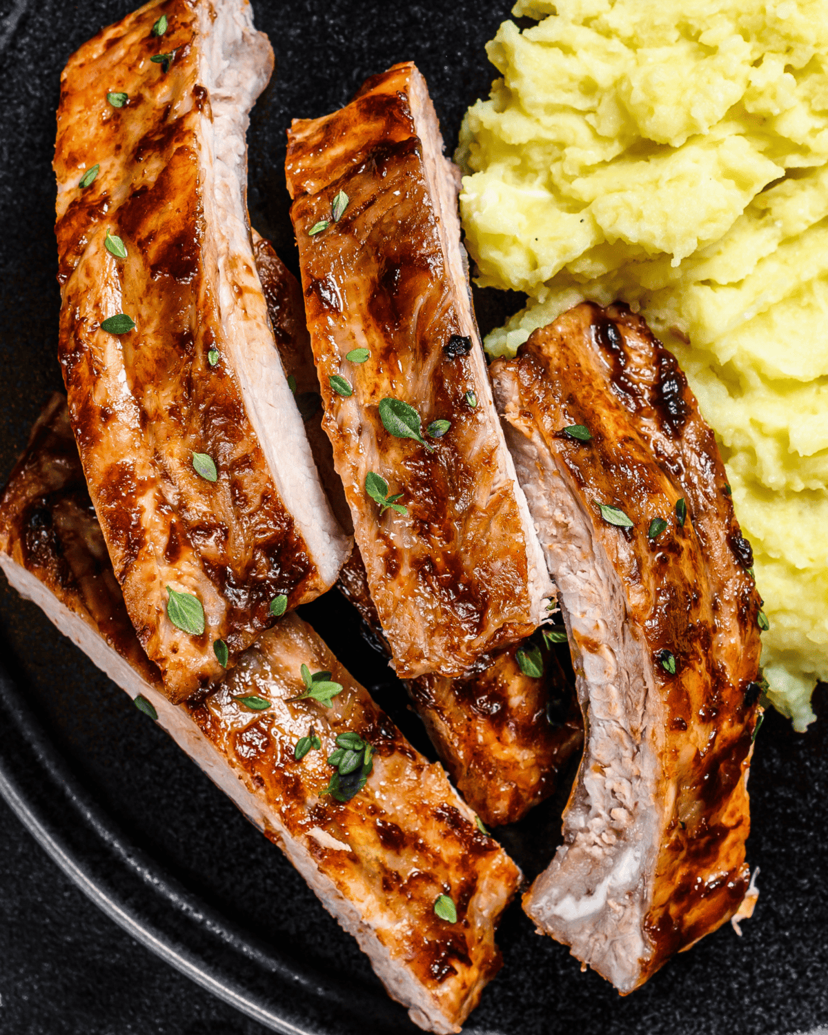 grilled baked pork ribs served with mashed potatoes in a plate. 